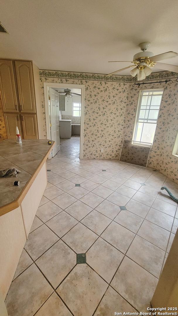7 Glen Cove Dr, Seguin, TX 78155 - spare room featuring wallpapered walls, ceiling fan, and light tile patterned floors