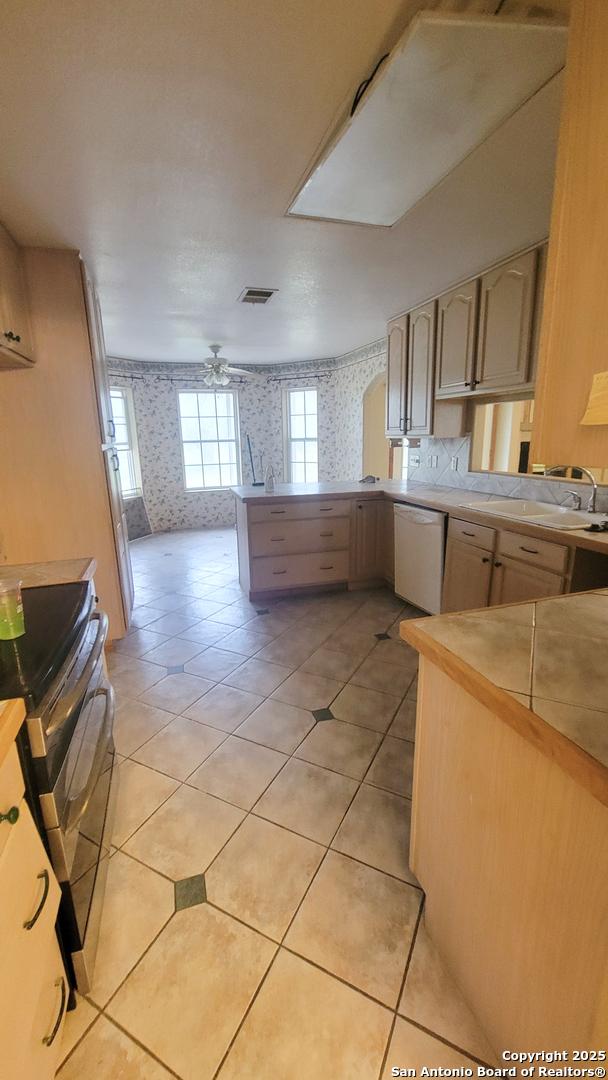 7 Glen Cove Dr, Seguin, TX 78155 - kitchen featuring wallpapered walls, dishwasher, double oven range, a peninsula, and ceiling fan