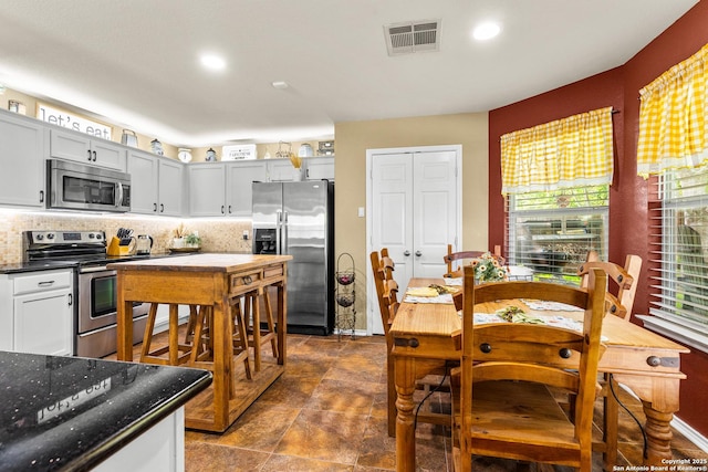 kitchen featuring stainless steel appliances, tasteful backsplash, recessed lighting, dark stone countertops, and dark stone finish floors