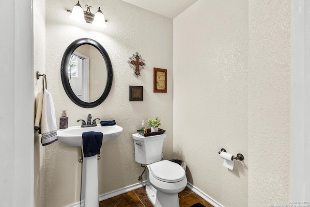 bathroom with toilet, baseboards, and a sink