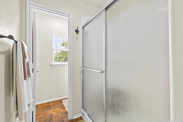 full bathroom featuring a shower stall and baseboards