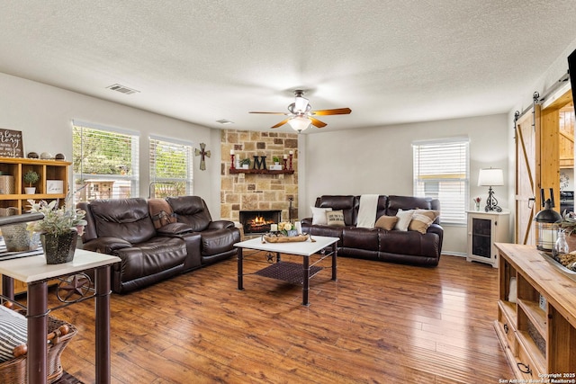 living room with hardwood / wood-style flooring, ceiling fan, plenty of natural light, a textured ceiling, and a barn door
