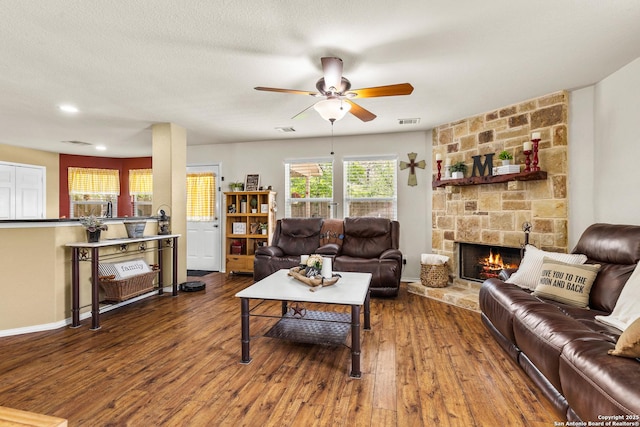 living room featuring a ceiling fan, wood finished floors, a fireplace, and baseboards