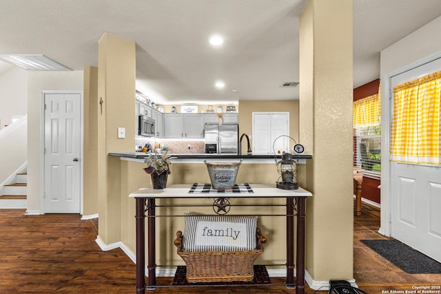 kitchen with stainless steel appliances, dark wood-style floors, baseboards, a peninsula, and recessed lighting