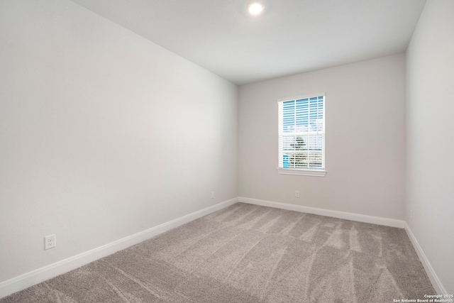 spare room with light carpet and baseboards