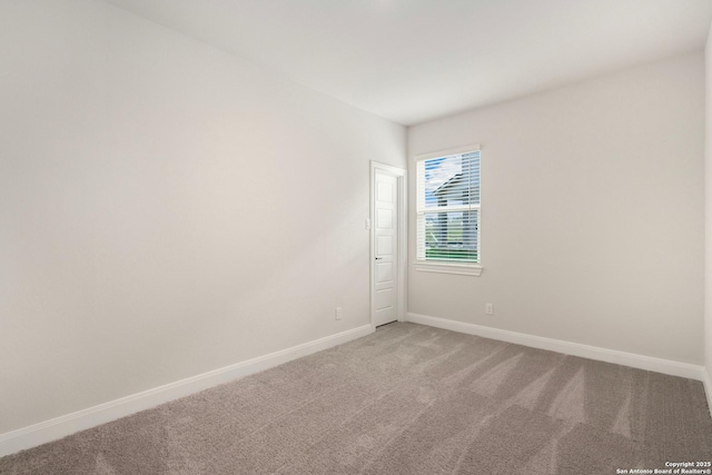 empty room featuring baseboards and light colored carpet
