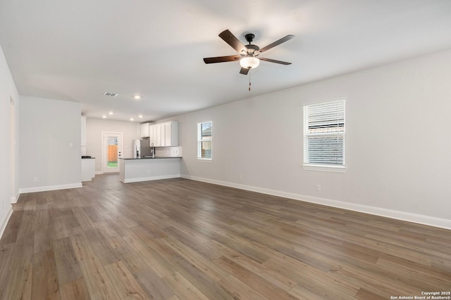 unfurnished living room with a ceiling fan, wood finished floors, baseboards, and recessed lighting