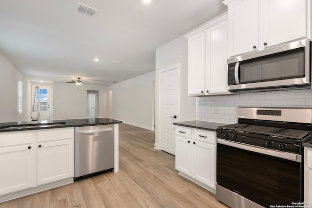kitchen featuring appliances with stainless steel finishes, tasteful backsplash, a sink, ceiling fan, and white cabinetry