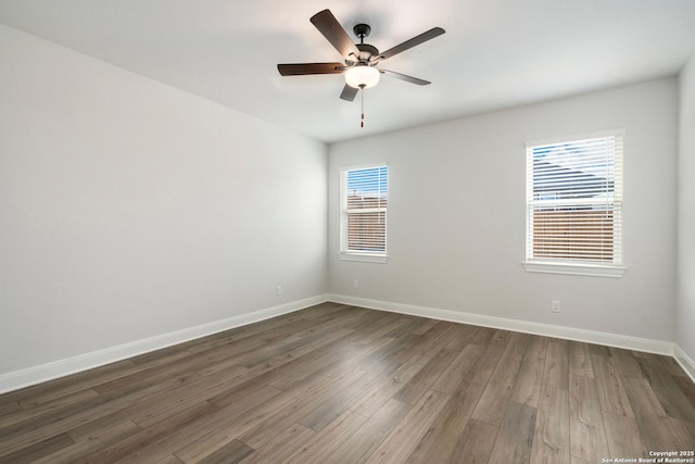 spare room with dark wood finished floors, baseboards, and a ceiling fan