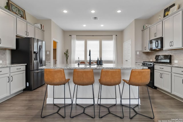 612 Wipper, New Braunfels, TX 78130 - kitchen featuring black microwave, gas range oven, stainless steel fridge with ice dispenser, backsplash, and a kitchen breakfast bar
