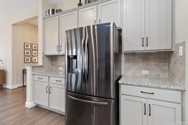 612 Wipper, New Braunfels, TX 78130 - kitchen with stainless steel fridge with ice dispenser, tasteful backsplash, light wood finished floors, baseboards, and light stone counters