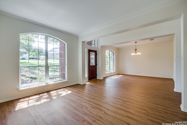 entrance foyer with a chandelier, wood finished floors, crown molding, and baseboards