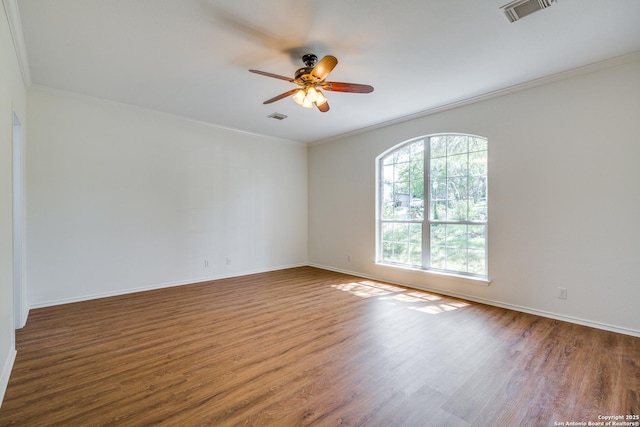 spare room with wood finished floors, a ceiling fan, crown molding, and baseboards