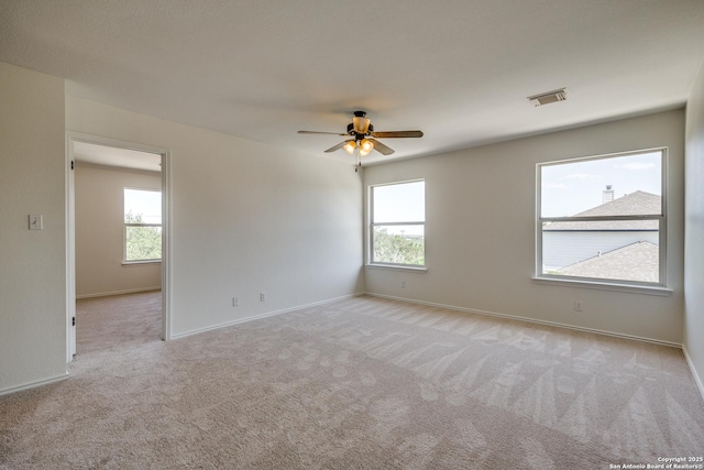 empty room featuring carpet, healthy amount of natural light, a ceiling fan, and baseboards
