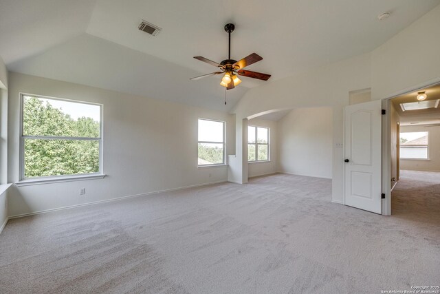 spare room featuring lofted ceiling, light carpet, a ceiling fan, arched walkways, and baseboards