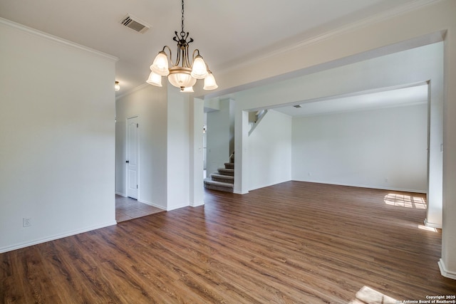 unfurnished room with a chandelier, crown molding, wood finished floors, stairs, and baseboards