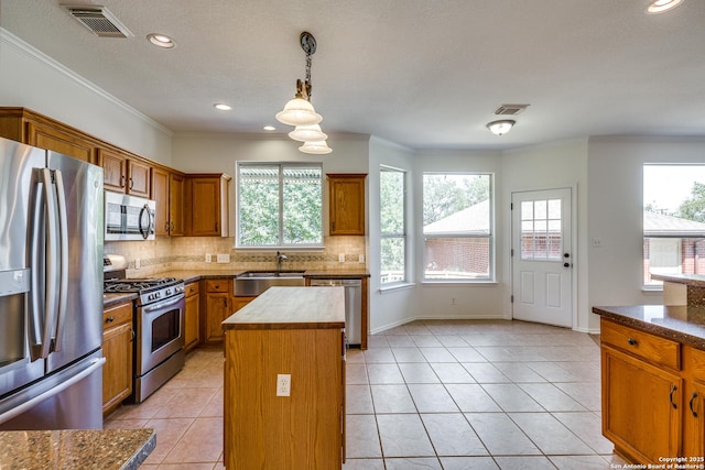 kitchen with stainless steel appliances, a kitchen island, brown cabinets, plenty of natural light, and recessed lighting