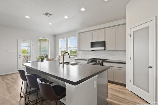 133 Edinburgh, Boerne, TX 78015 - kitchen with white microwave, a sink, stainless steel range with gas cooktop, dark countertops, and a kitchen island with sink