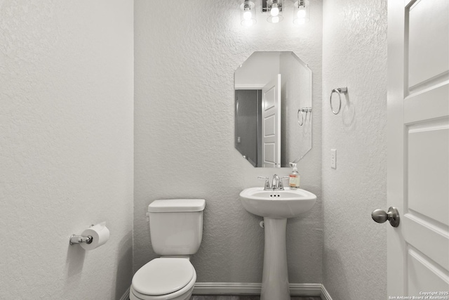 133 Edinburgh, Boerne, TX 78015 - bathroom with toilet, a textured wall, a sink, and baseboards