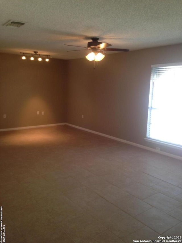 empty room featuring ceiling fan, a textured ceiling, and baseboards