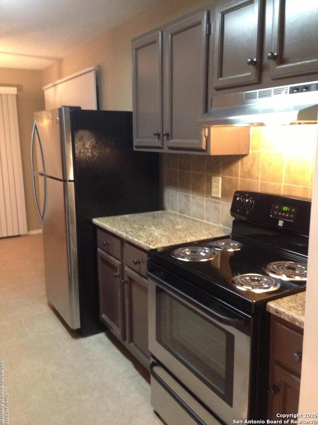 kitchen featuring appliances with stainless steel finishes, under cabinet range hood, backsplash, and light flooring