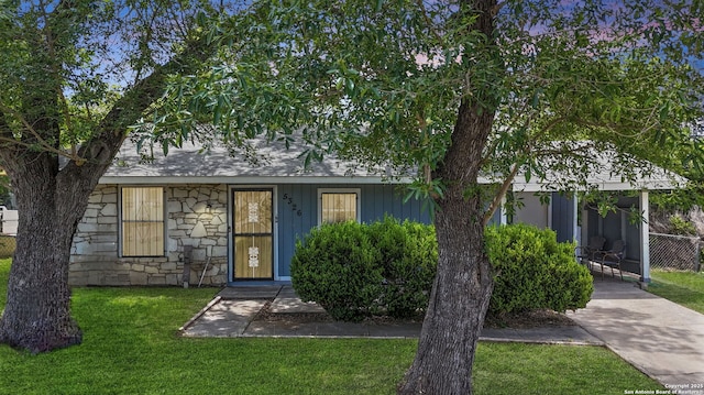 view of front of home featuring stone siding, a front yard, and a carport