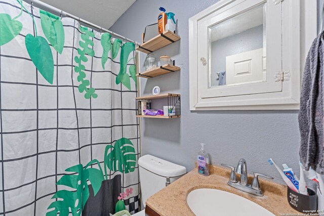 full bath featuring curtained shower, toilet, vanity, and a textured wall