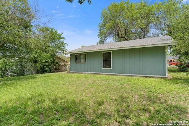 back of house featuring a yard and roof with shingles