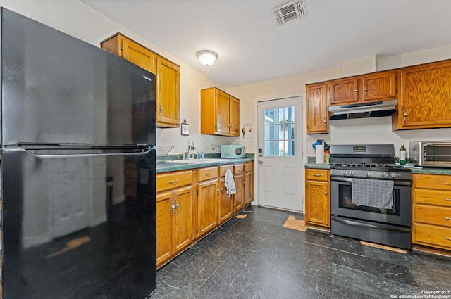 kitchen with freestanding refrigerator, stainless steel range with gas cooktop, under cabinet range hood, a sink, and white microwave