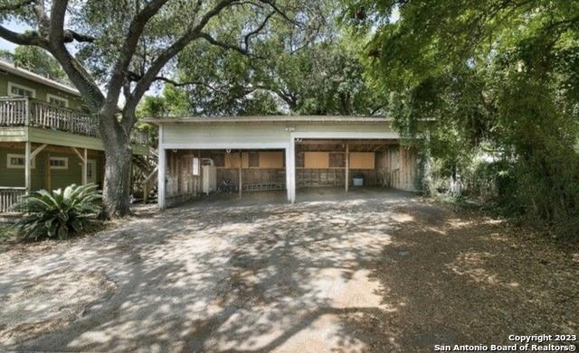 garage with a carport and dirt driveway