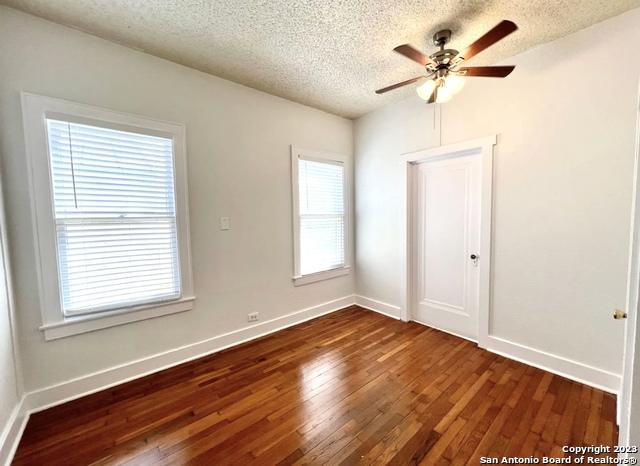spare room with dark wood finished floors, a textured ceiling, ceiling fan, and baseboards