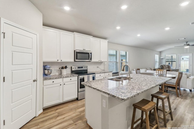 3012 Hess Blvd, Schertz, TX 78154 - kitchen with appliances with stainless steel finishes, a sink, tasteful backsplash, light wood-style floors, and a kitchen bar