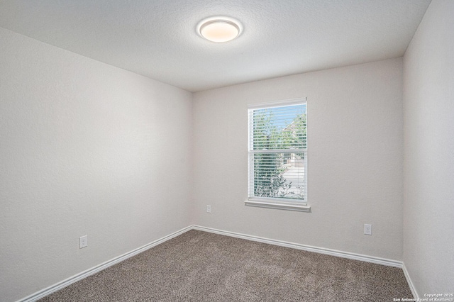 unfurnished room featuring dark carpet and baseboards