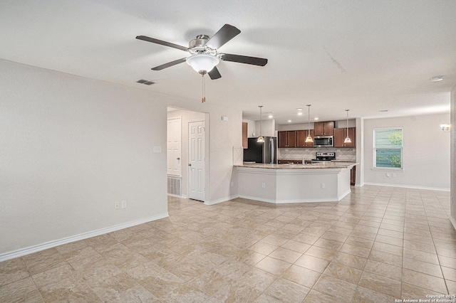 kitchen with appliances with stainless steel finishes, tasteful backsplash, open floor plan, ceiling fan, and a peninsula