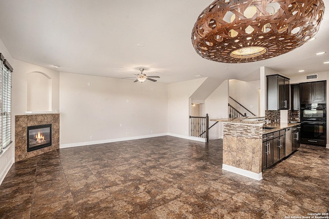23807 Stately Oaks, San Antonio, TX 78260 - kitchen featuring ceiling fan, a tiled fireplace, open floor plan, baseboards, and light stone counters