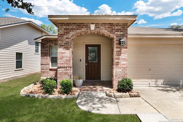 entrance to property with brick siding, a garage, driveway, and a lawn