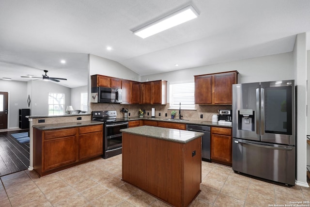 kitchen with appliances with stainless steel finishes, lofted ceiling, a sink, decorative backsplash, and a peninsula