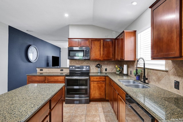 kitchen featuring appliances with stainless steel finishes, a sink, lofted ceiling, backsplash, and stone counters