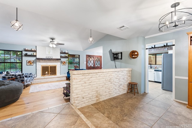 kitchen featuring appliances with stainless steel finishes, tile patterned flooring, a fireplace, ceiling fan, and a chandelier