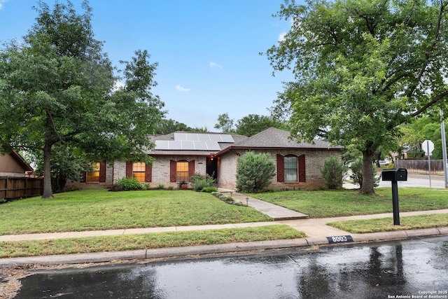view of front of home featuring roof mounted solar panels and brick siding