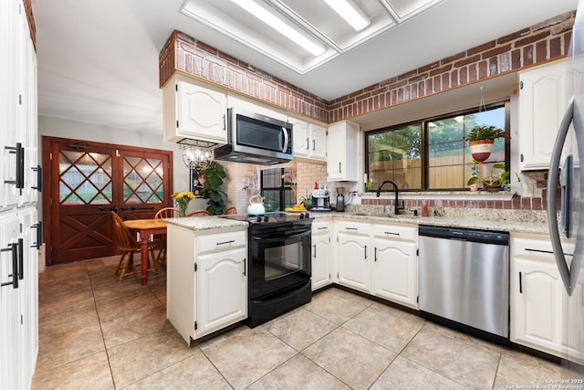 kitchen with stainless steel appliances, a sink, a peninsula, decorative backsplash, and light tile patterned floors
