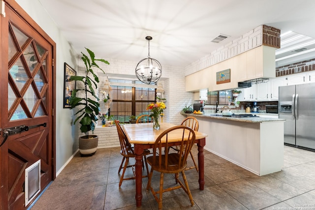 dining area with a chandelier and brick wall