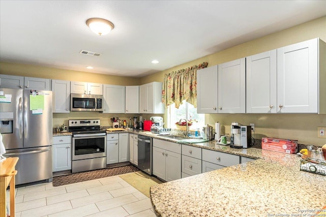 205 Montrose, Liberty Hill, TX 78642 - kitchen featuring appliances with stainless steel finishes, a sink, recessed lighting, light stone countertops, and a peninsula