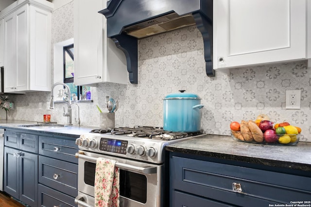 kitchen with stainless steel gas range oven, white cabinets, a sink, and decorative backsplash