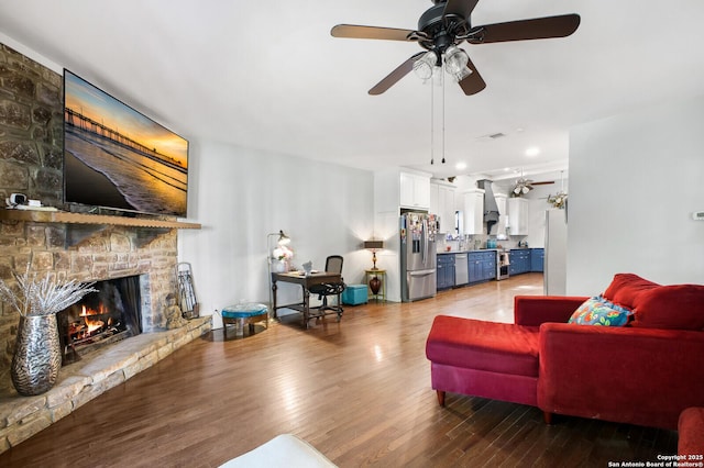 living room featuring ceiling fan, a fireplace, wood finished floors, and recessed lighting