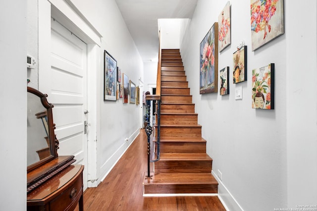 stairway with wood finished floors and baseboards