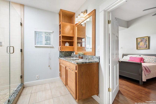 full bath featuring a shower stall, tasteful backsplash, baseboards, ceiling fan, and vanity