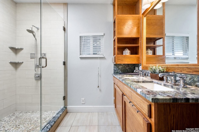 bathroom with a shower stall, baseboards, and double vanity