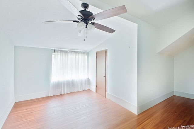 unfurnished room with wood finished floors, ceiling fan, baseboards, and vaulted ceiling