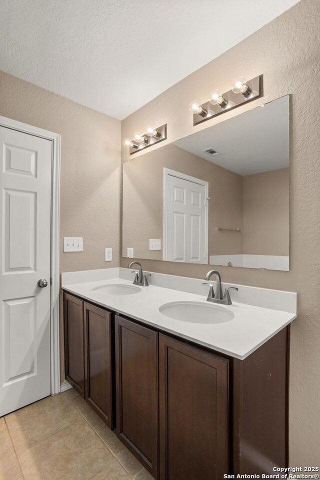 1617 Desert Candle, San Antonio, TX 78245 - bathroom with tile patterned flooring, a textured wall, and double vanity